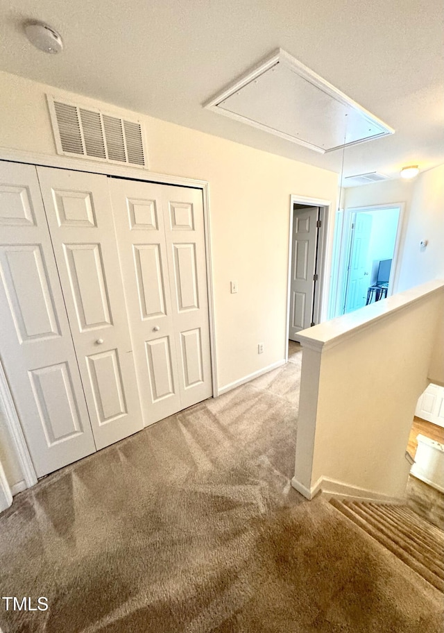 hall featuring attic access and light carpet