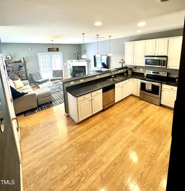 kitchen with stainless steel appliances, a sink, a peninsula, open floor plan, and recessed lighting