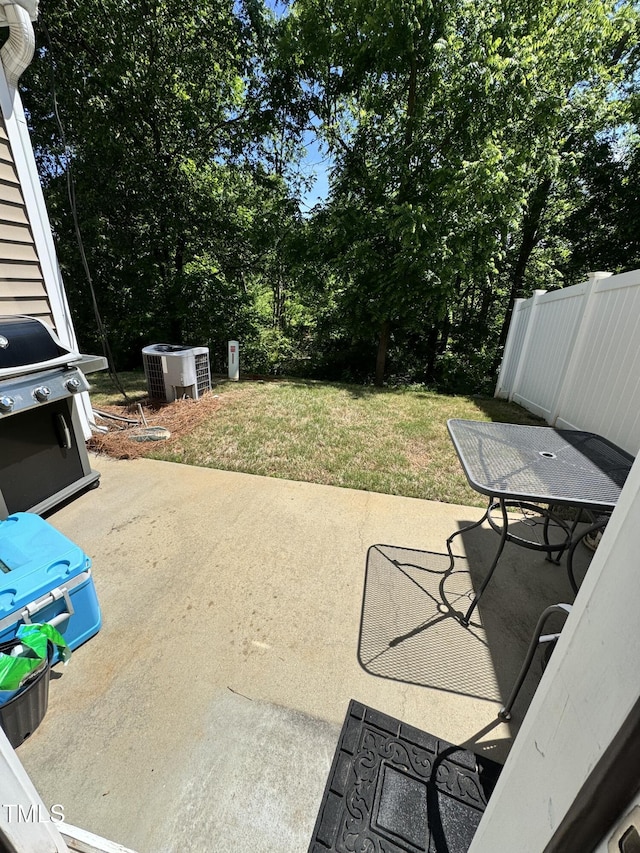 view of patio featuring central AC, a grill, and view of wooded area