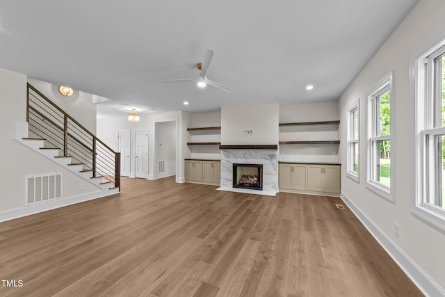 525 Allesandra Dr, Clayton, NC 27527 - unfurnished living room with a ceiling fan, baseboards, light wood-style floors, stairway, and a premium fireplace