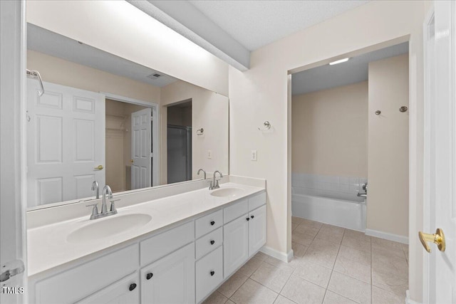 full bath featuring baseboards, tile patterned floors, double vanity, and a bath