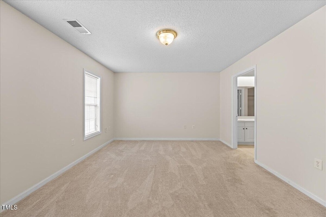 carpeted empty room with a textured ceiling and baseboards