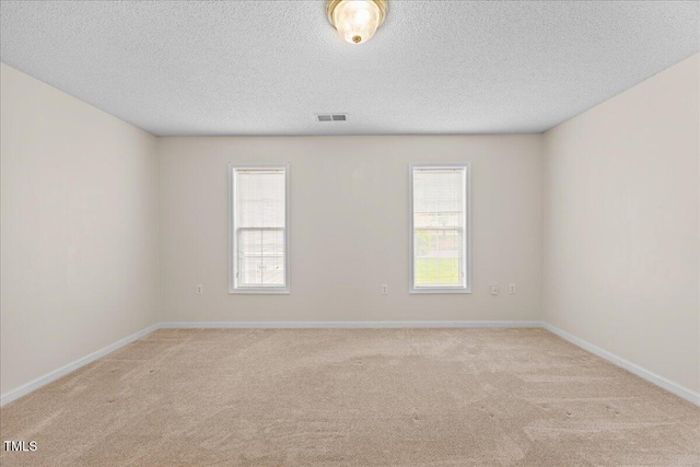 spare room with carpet floors, a textured ceiling, and baseboards