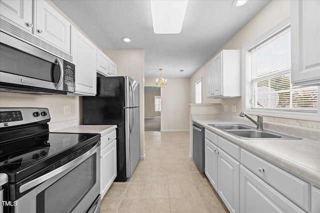 kitchen with stainless steel appliances, a sink, a chandelier, white cabinetry, and a textured ceiling