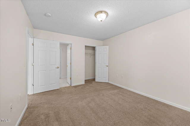 unfurnished bedroom with carpet flooring, a textured ceiling, baseboards, and a closet