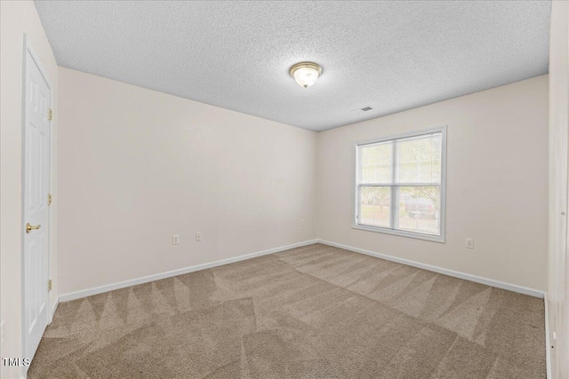 carpeted spare room with a textured ceiling and baseboards