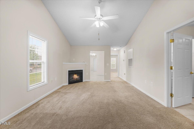 unfurnished living room with light carpet, a lit fireplace, lofted ceiling, ceiling fan, and baseboards