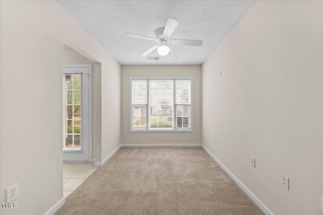 carpeted empty room with a textured ceiling, ceiling fan, and baseboards