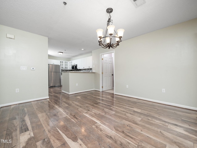 1911 Falls Landing Dr Unit 106, Raleigh, NC 27614 - unfurnished living room featuring wood-type flooring, a chandelier, and baseboards