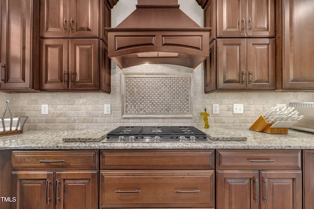 4802 Glenmist Ct, Raleigh, NC 27612 - kitchen with custom range hood, stainless steel gas stovetop, decorative backsplash, and light stone countertops