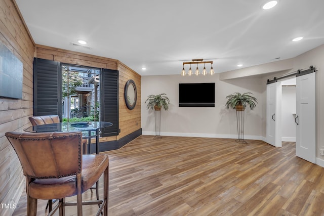 4802 Glenmist Ct, Raleigh, NC 27612 - living area featuring a barn door, light wood-style flooring, recessed lighting, baseboards, and wooden walls