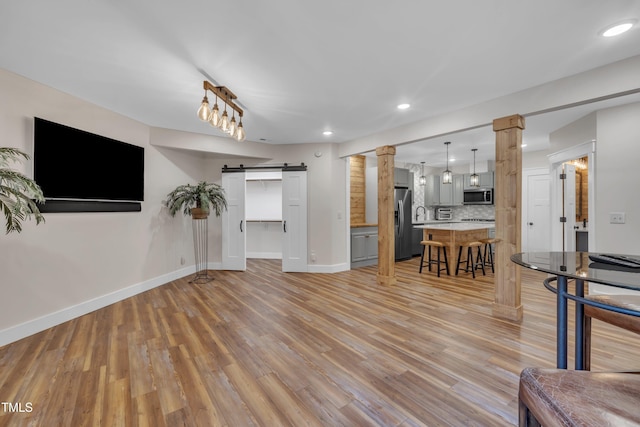 4802 Glenmist Ct, Raleigh, NC 27612 - living room featuring a barn door, light wood-style flooring, baseboards, recessed lighting, and ornate columns