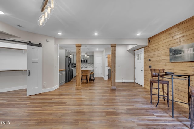 4802 Glenmist Ct, Raleigh, NC 27612 - living area featuring a barn door, baseboards, recessed lighting, light wood-style flooring, and wooden walls