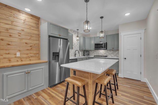 4802 Glenmist Ct, Raleigh, NC 27612 - kitchen featuring stainless steel appliances, a sink, light wood-style floors, a kitchen bar, and decorative backsplash
