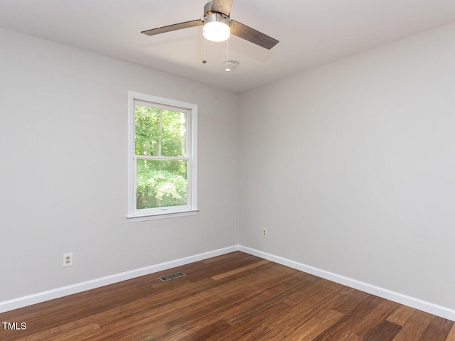 empty room with dark wood-style floors, baseboards, and ceiling fan