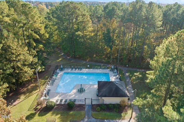 aerial view of property and surrounding area featuring a heavily wooded area and a pool area