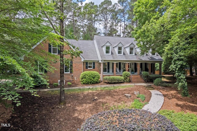 new england style home with covered porch and brick siding