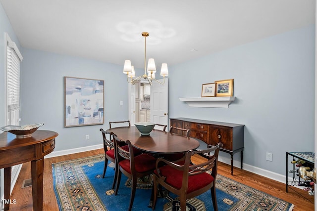 dining area with wood finished floors, a chandelier, and baseboards