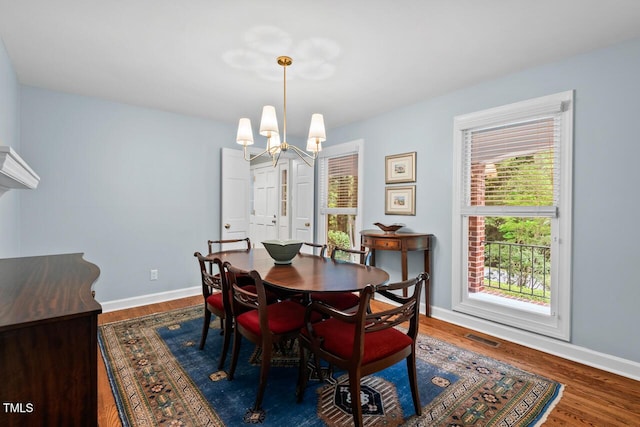 dining space featuring a chandelier, wood finished floors, and baseboards