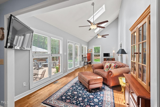 living room featuring a ceiling fan, high vaulted ceiling, wood finished floors, and baseboards