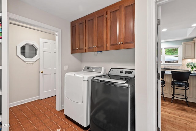 clothes washing area with washer and clothes dryer, cabinet space, recessed lighting, and baseboards