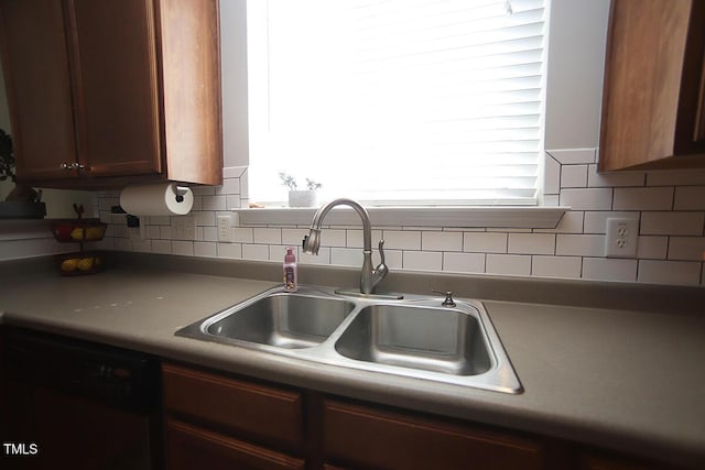 kitchen featuring a sink, dishwashing machine, and backsplash