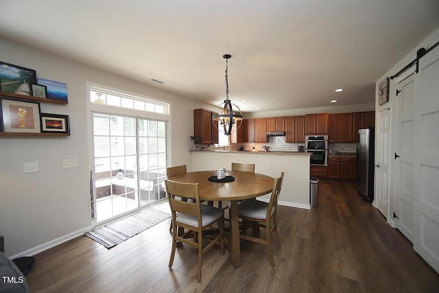 dining space with a chandelier, dark wood-type flooring, recessed lighting, a barn door, and baseboards