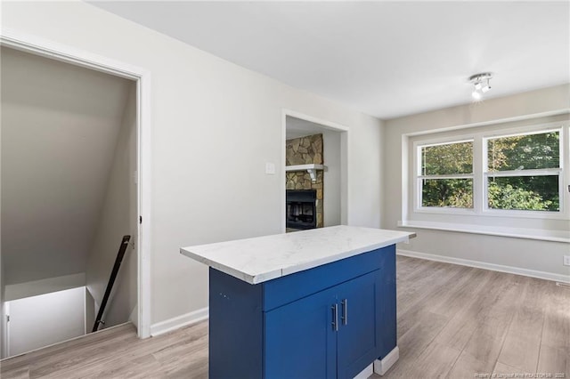 70 Oregon Ln, Spring Lake, NC 28390 - kitchen with blue cabinets, light wood-type flooring, a stone fireplace, baseboards, and a center island