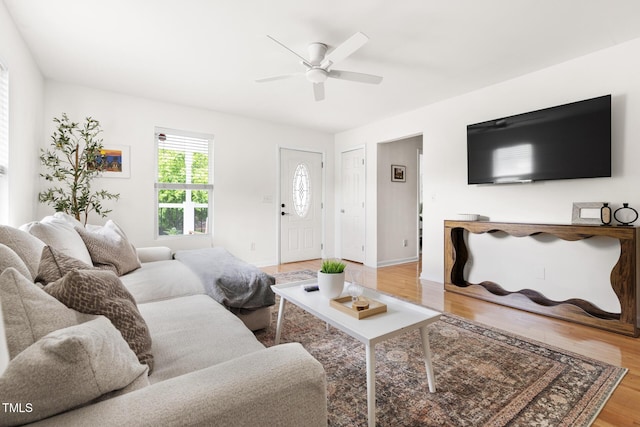 living area with light wood-style flooring, ceiling fan, and baseboards