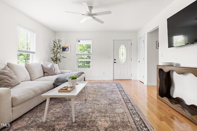 living area with light wood-style flooring, ceiling fan, and baseboards