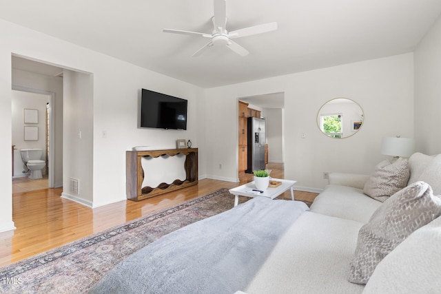 living area with ceiling fan, light wood-style floors, and baseboards
