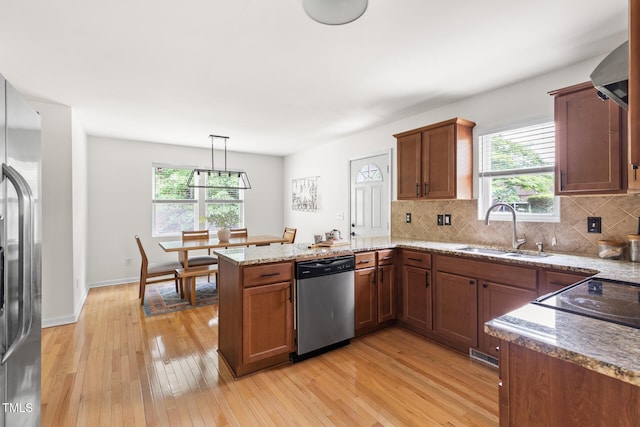 kitchen featuring stainless steel appliances, a sink, a peninsula, and plenty of natural light