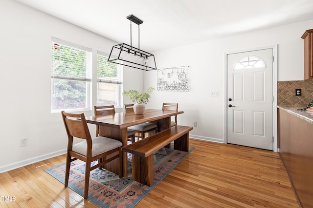 dining room with light wood-type flooring, baseboards, and a chandelier
