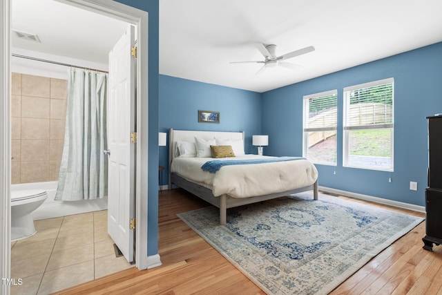 bedroom with baseboards, light wood finished floors, a ceiling fan, and connected bathroom