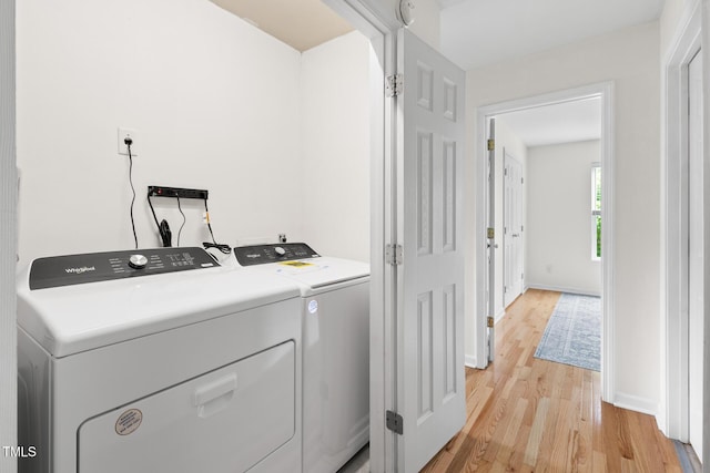 washroom with washer and dryer, light wood-type flooring, and baseboards
