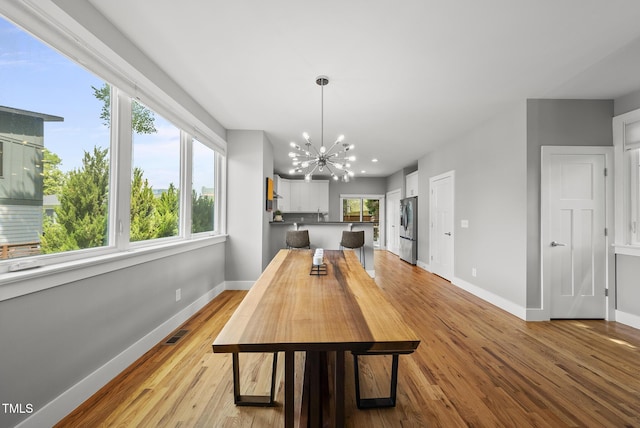 dining space featuring a chandelier, baseboards, and light wood-type flooring