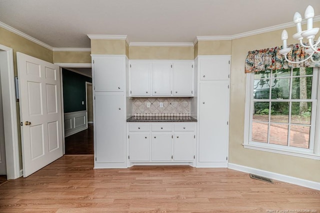 225 Lakeview Dr, Sanford, NC 27332 - kitchen featuring dark countertops, light wood-style flooring, white cabinets, crown molding, and tasteful backsplash