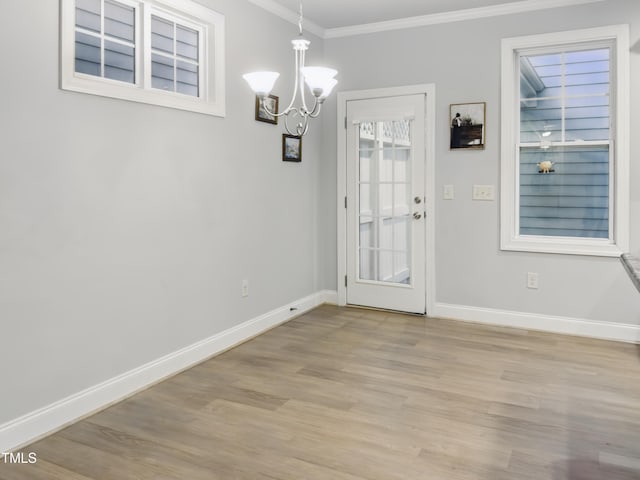 unfurnished dining area featuring crown molding, baseboards, light wood-style flooring, and a chandelier