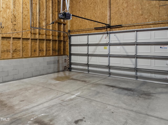 garage with a garage door opener and concrete block wall