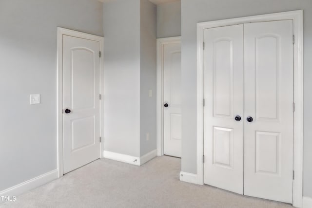unfurnished bedroom featuring light colored carpet, baseboards, and a closet
