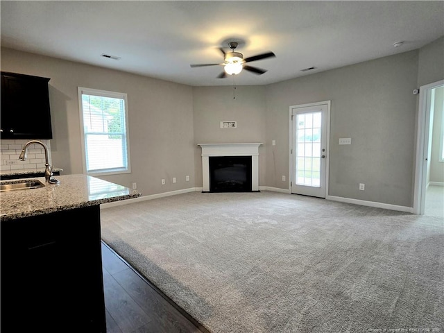 338 E David Parnell St, Parkton, NC 28371 - unfurnished living room with ceiling fan, a fireplace with flush hearth, light carpet, and light wood finished floors
