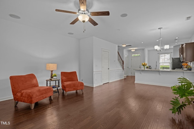 living area featuring stairway, wood finished floors, a chandelier, and a ceiling fan