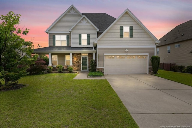 view of front of home with an attached garage, driveway, stone siding, and a front lawn