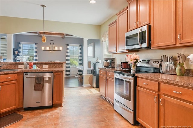 kitchen with stainless steel appliances, decorative columns, arched walkways, pendant lighting, and recessed lighting
