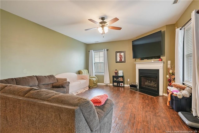 living room with wood finished floors, a fireplace with flush hearth, ceiling fan, and baseboards