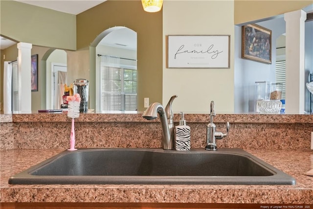 kitchen view of a sink, decorative columns, and arched walkways