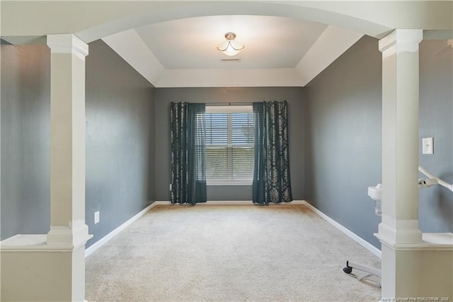 spare room featuring arched walkways, carpet, ornate columns, and baseboards