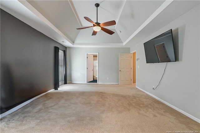 unfurnished bedroom with vaulted ceiling, carpet flooring, baseboards, a tray ceiling, and ceiling fan