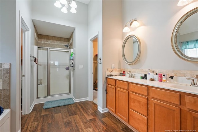 full bath with wood finished floors, a stall shower, double vanity, and a chandelier