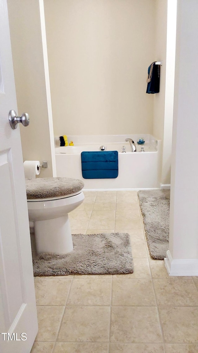 full bathroom featuring a garden tub, tile patterned flooring, toilet, and baseboards